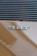 A close-up view of a car badge displaying the text '911T' on a smooth, reflective surface. The badge is metallic and prominently positioned against a light brown or bronze background. Horizontal vents or grille lines are visible above the badge, adding texture.