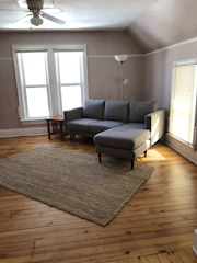 A spacious living room bathed in soft gray tones with plush seating and golden lighting fixtures.