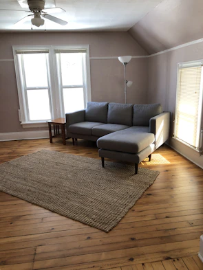 Bright living room featuring sleek vinyl flooring paired with soft beige walls and charcoal gray accents.