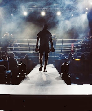 man standing and walking going on boxing ring surrounded with people
