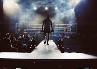 man standing and walking going on boxing ring surrounded with people