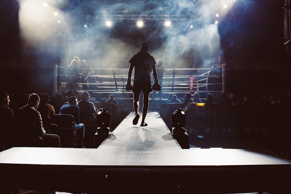 man standing and walking going on boxing ring surrounded with people