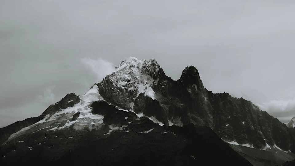 Majestic mountain range with snow-capped peaks against an overcast gray-brown sky landscape