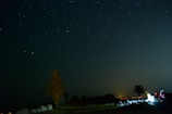 A tranquil night sky filled with stars above a quiet landscape.