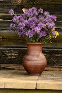 A textured glaze vase holding fresh wildflowers on a wooden table