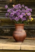 A rustic ceramic vase filled with fresh wildflowers on a vintage sideboard.