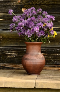 A textured glaze vase holding fresh wildflowers on a wooden table