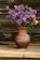 Close-up of a textured glaze vase holding fresh wildflowers on a wooden table.