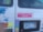 The image shows the back of a vehicle with multiple stickers and a Minnesota license plate (343 TTM). Some notable stickers include a pink one that reads 'The Women are coming. Expect Us.' and other stickers with various messages and colorful designs. The inside of the vehicle appears cluttered with different items visible through the window.