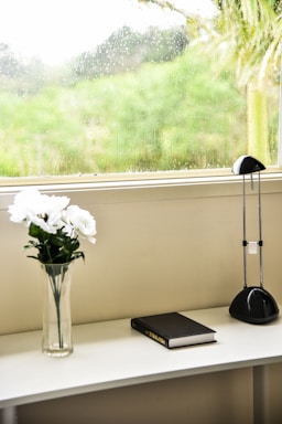 A welcoming church office with a warm wooden desk and a vase of fresh flowers beside a phone and a notebook.