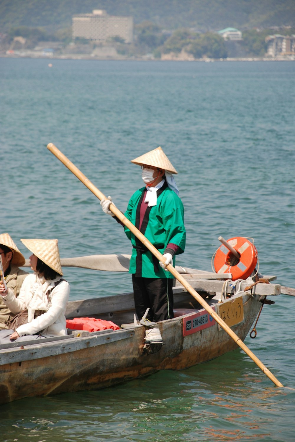 person in boat while 1 is holding a bamboo pole