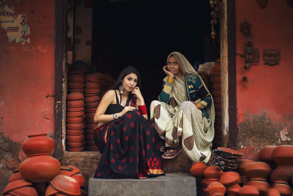 two woman sitting on concrete stairs