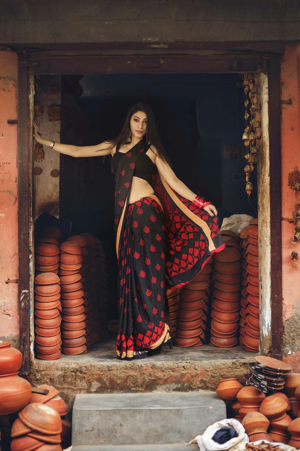 woman in salwar kameez standing by open door surround with pots