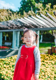 A cheerful child twirling in a colorful kids' dress in a sunny garden.