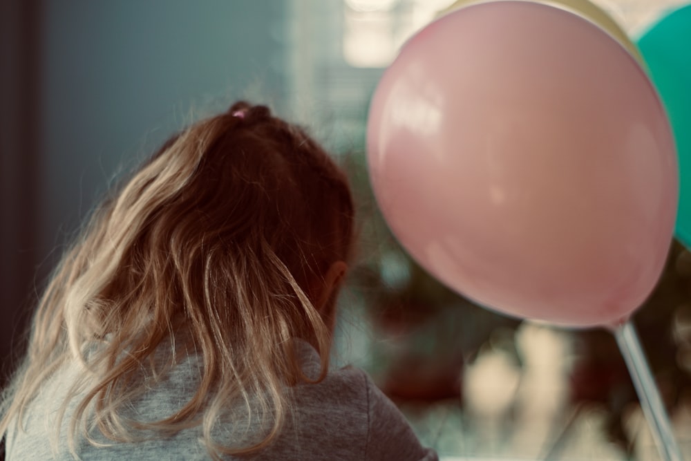 girl in gray shirt beside pink balloon