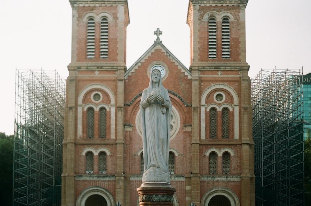 Virgin Mary statue in front of brown cathedral