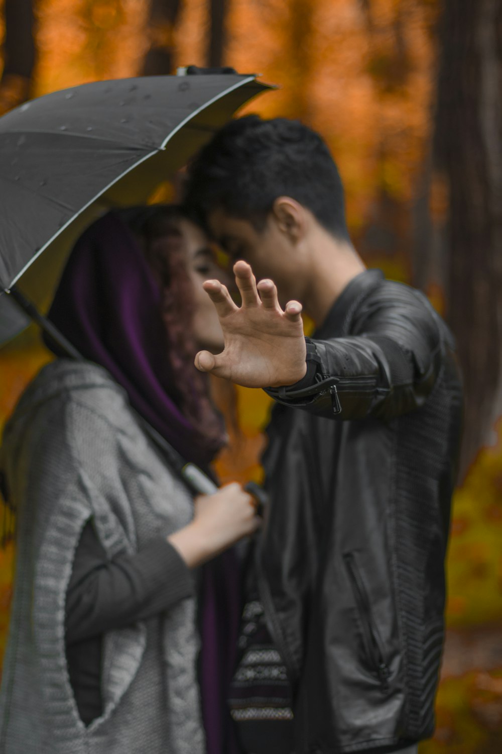 man and woman kissing under umbrella