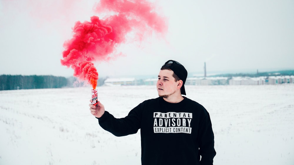 man in black jacket holding a red smoke toy