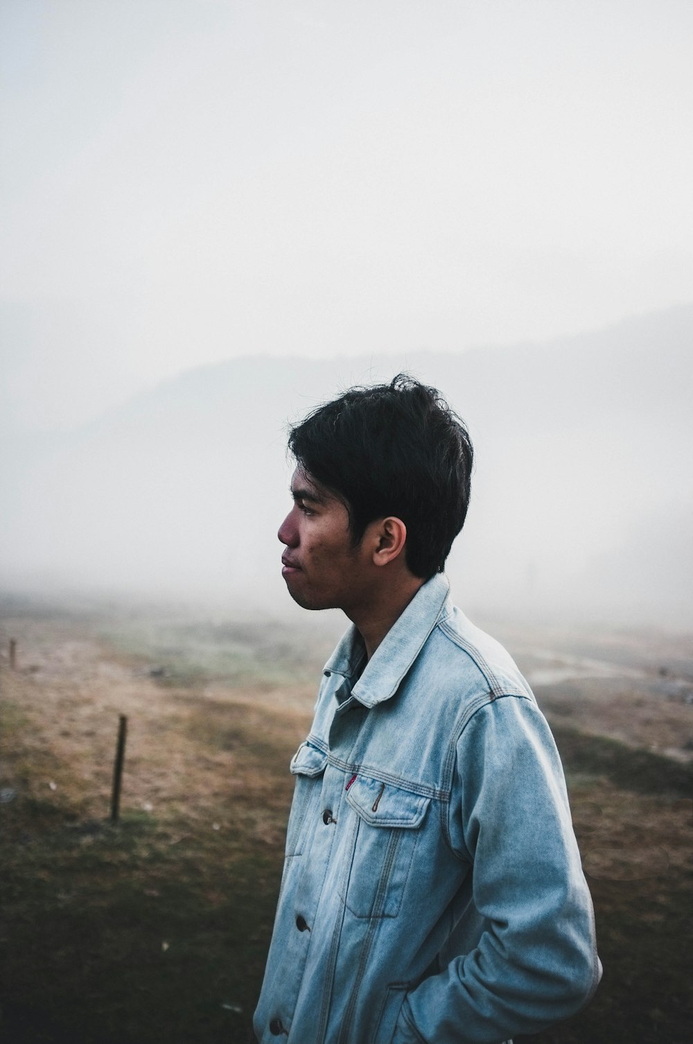 man wearing blue denim jacket under foggy weather