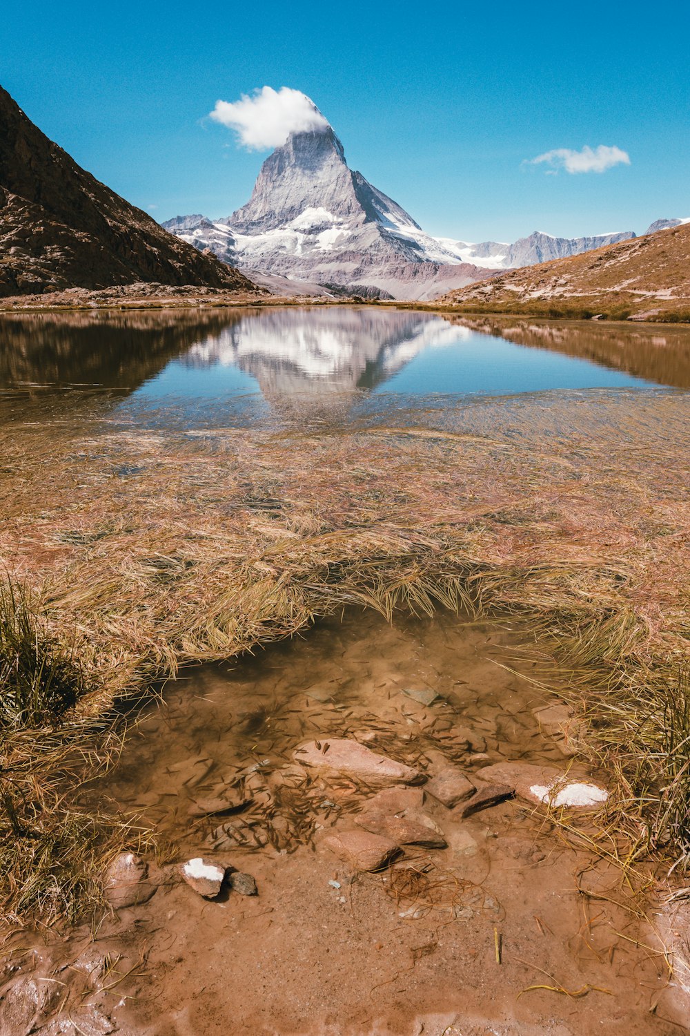 body of water near rocky mountain during daytime