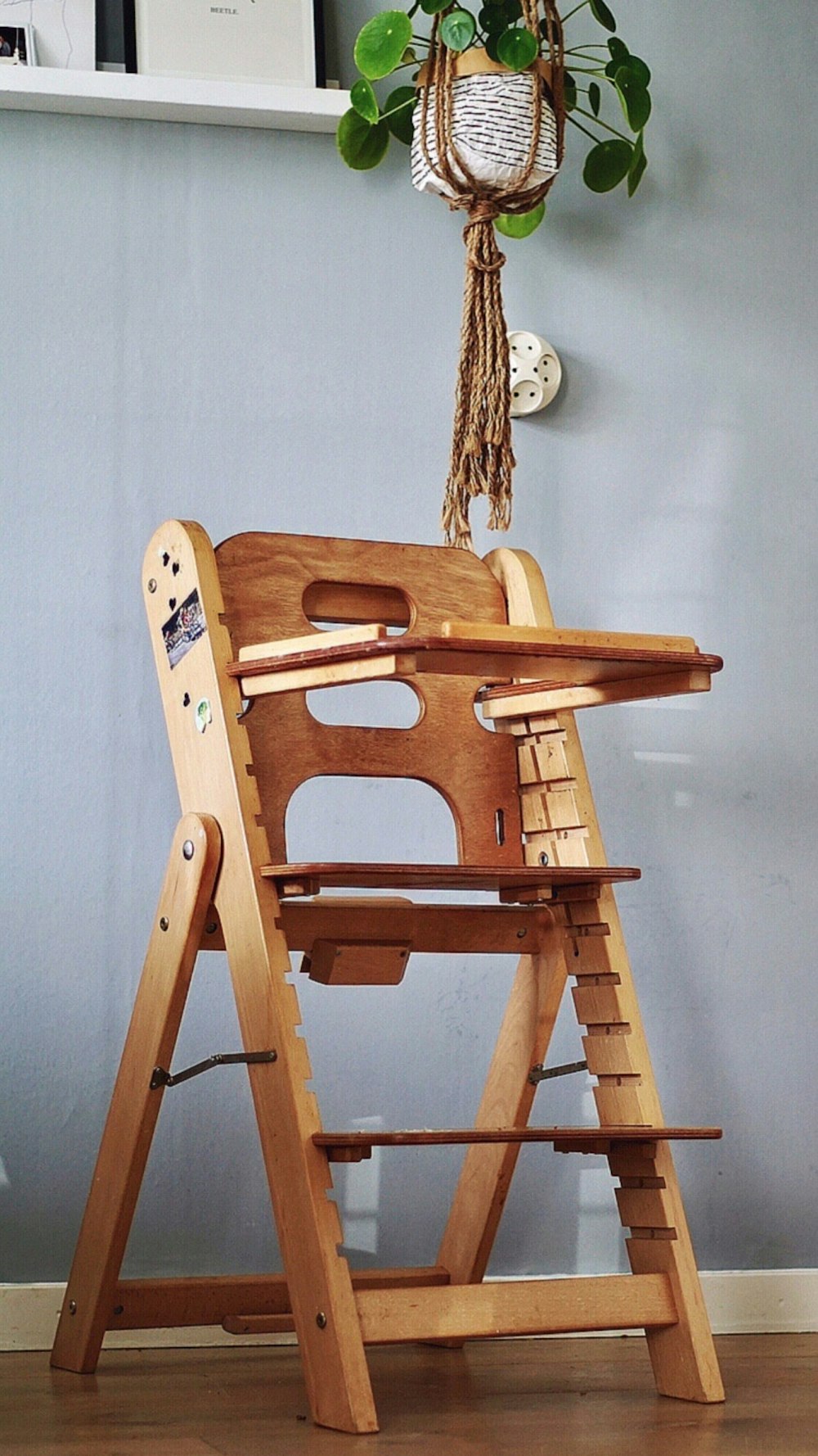 a wooden high chair with a plant hanging from it