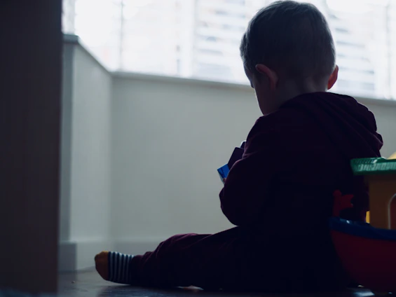 A child happily playing with colorful wooden toys in a sunlit room filled with natural elements.