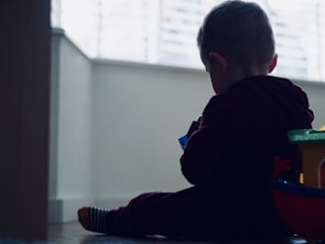 A toddler playing happily with colorful wooden toys on a sunny playroom floor.