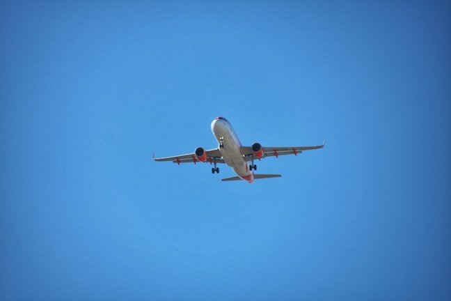 A sleek commercial airplane taxiing on the runway under a clear blue sky.
