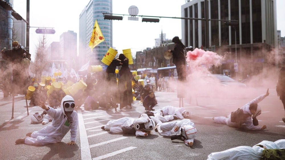 people wearing scrub suits lying on road covered with smoke