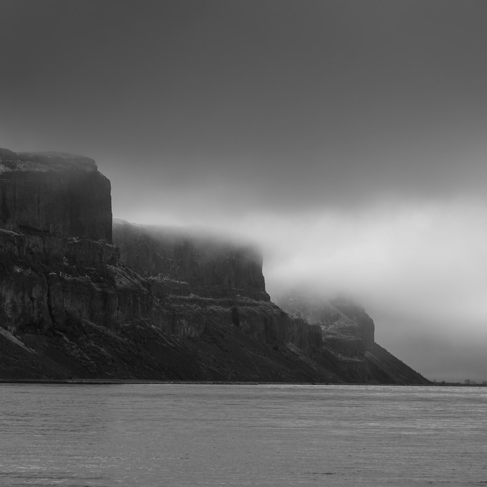 grayscale photography of mountains beside sea