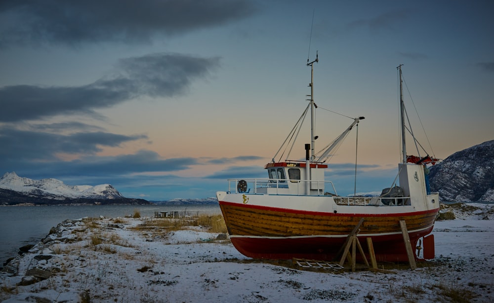 Rotes und weißes Holzboot in der Nähe der Küste