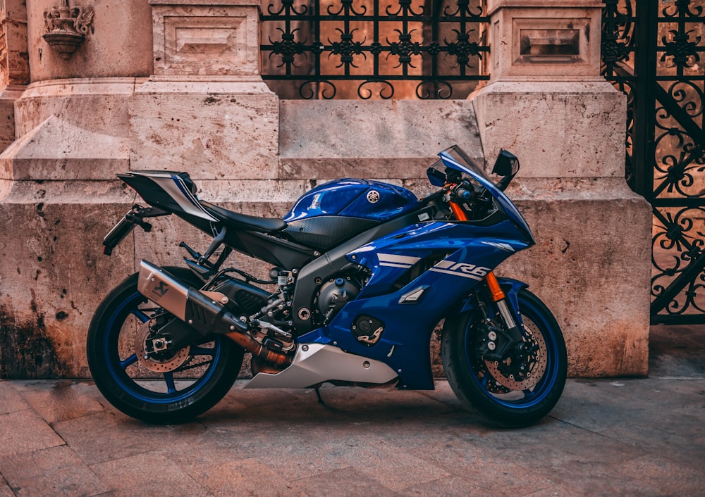 parked blue sports bike near black metal gate