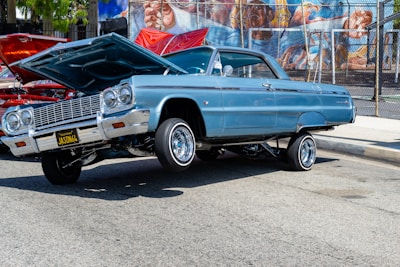 A sleek lowrider with a candy paint job and hydraulics mid-bounce at a club meet.