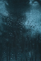 A close-up of a surface covered in water droplets and moisture, creating a textured and glossy appearance. The droplets vary in size and are densely packed, suggesting condensation or humidity.