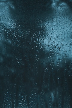 A close-up of a surface covered in water droplets and moisture, creating a textured and glossy appearance. The droplets vary in size and are densely packed, suggesting condensation or humidity.