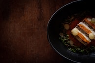 Close-up of a traditional dish being artfully plated in a rustic kitchen.