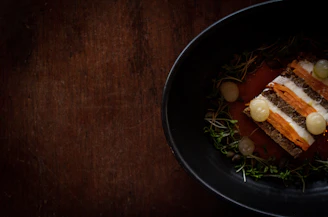 Close-up of a rustic dish being plated in a Scandinavian-style restaurant setting.