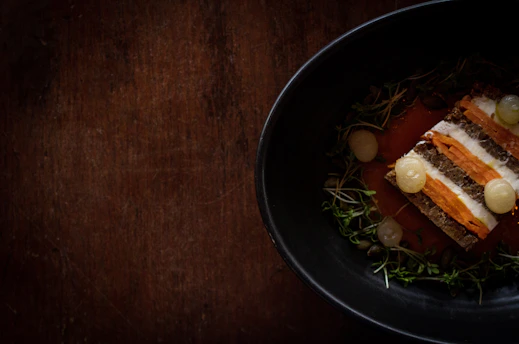 Close-up of a rustic dish being plated in a Scandinavian-style restaurant setting.