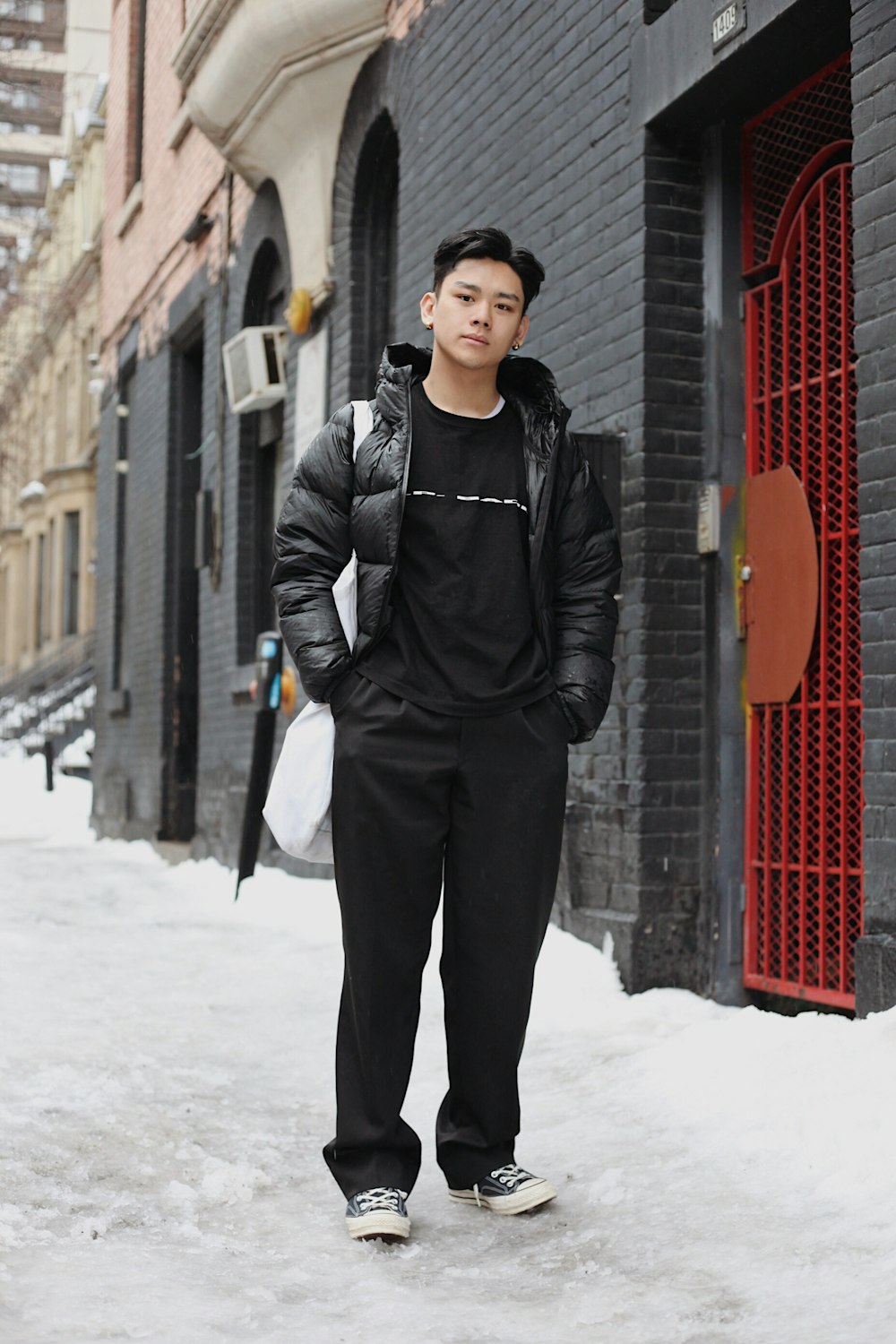 man wearing bubble jacket standing near red gate during daytime