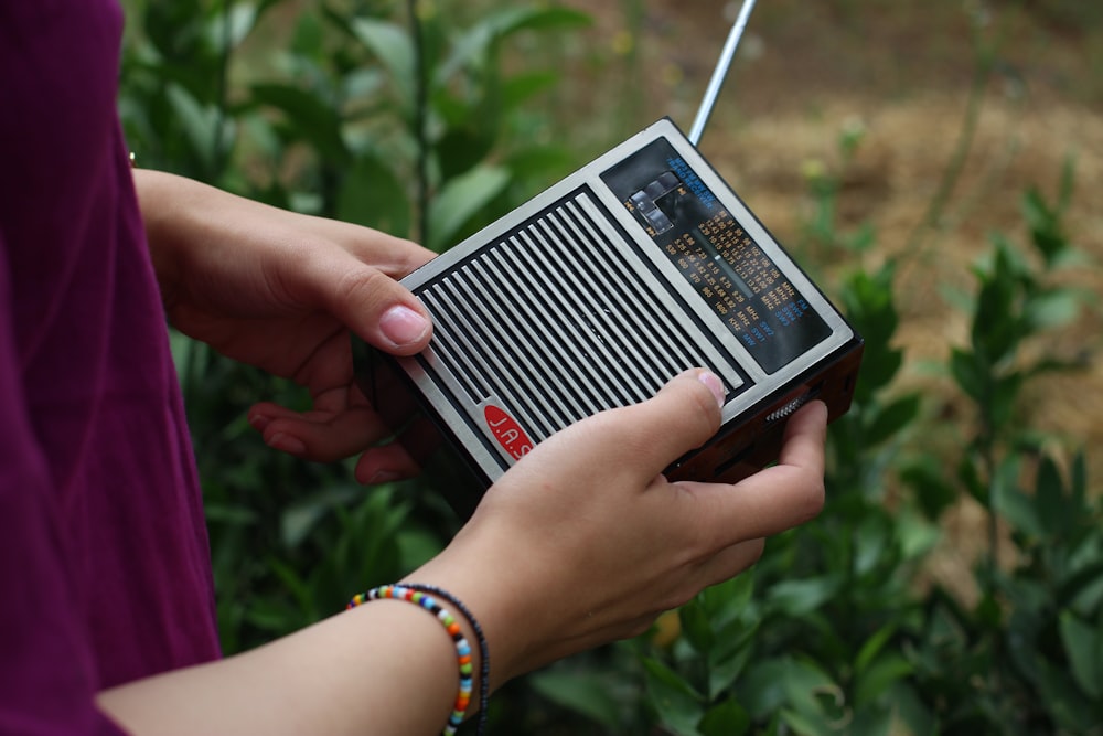 person holding black and gray radio