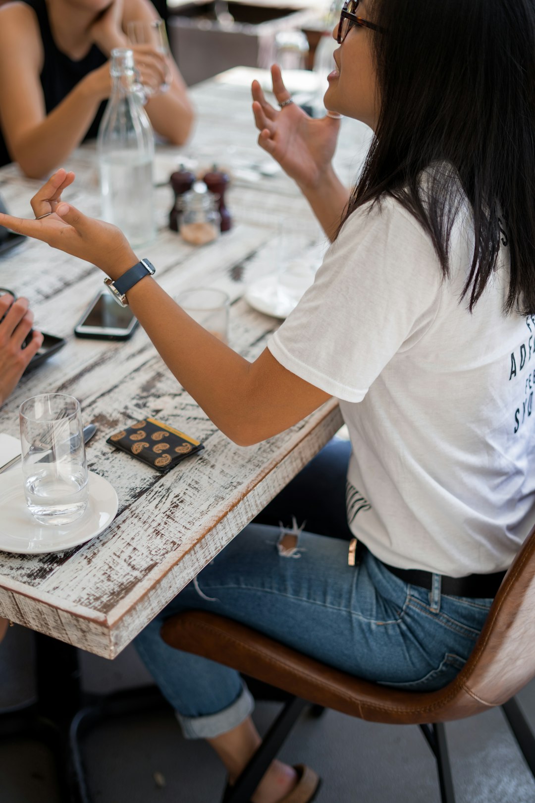 asian woman sitting at a table talking to others 