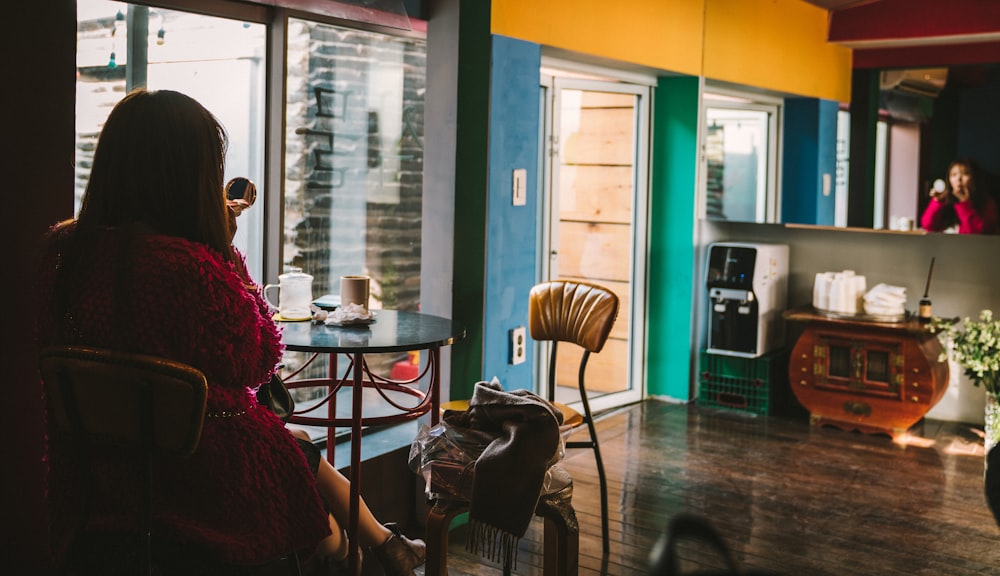 woman in red on chair next to window