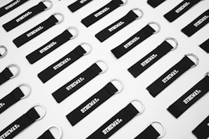 A set of custom laser-engraved metal keychains arranged neatly on a matte black background