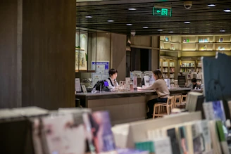 A mentor and mentee engaged in a thoughtful conversation in a cozy library setting.