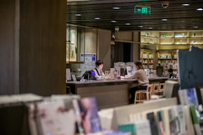 A mentor and student engaged in a lively conversation over books in a cozy library corner.