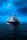 A large blue cargo ship is prominently positioned in the middle of a calm sea under a vast, somewhat cloudy sky. The ship has several antennas and cranes on deck, with the name 'XINRUI' visible on its hull.