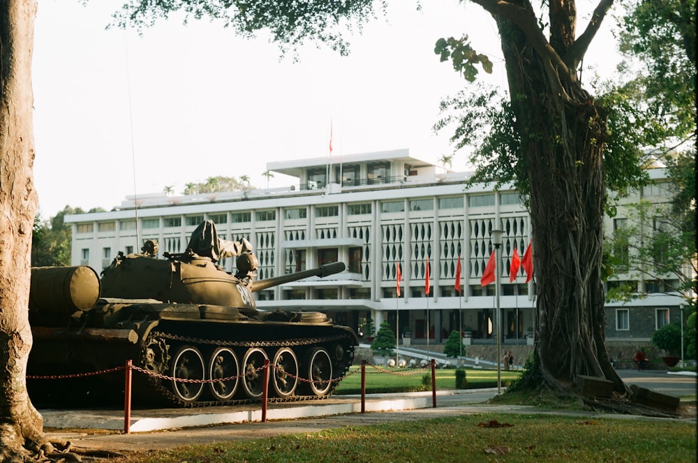 Tanque de batalla junto a los árboles frente al edificio blanco