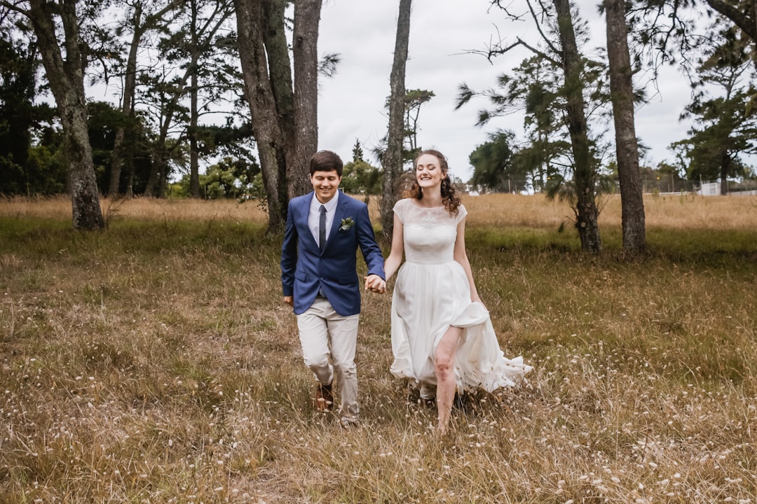 woman wearing white gown holding hands with man wearing blue blazer