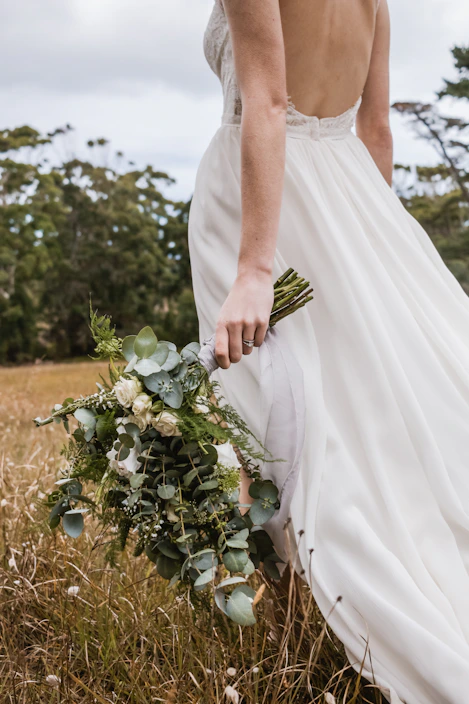 woman in white wedding dress with bouquet of flowers in hand