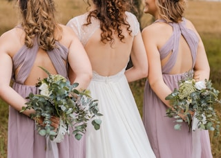 three women hiding flower bouquets